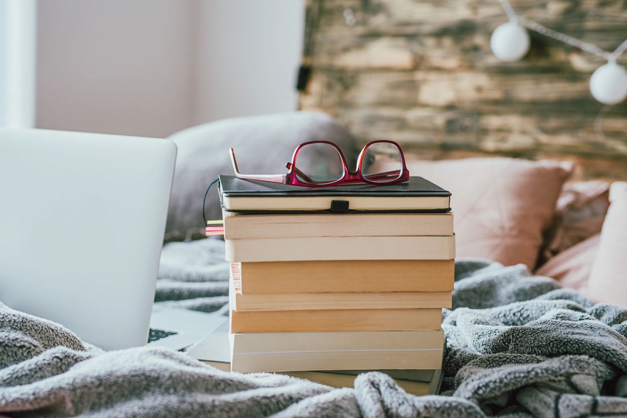 Stack of books with glasses on a bed